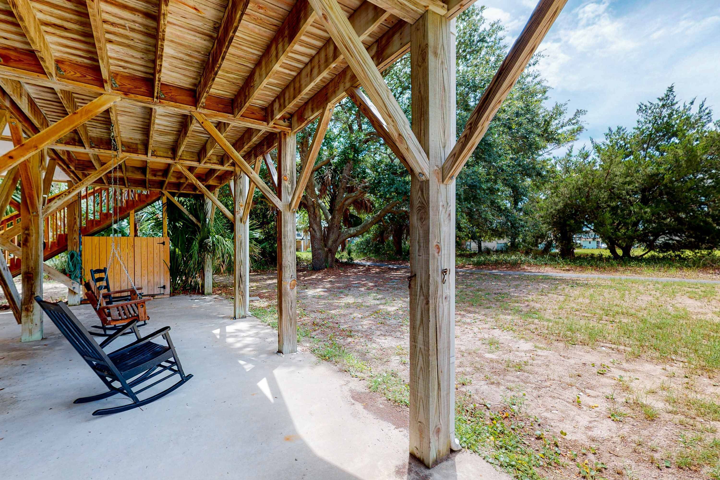 A wooden structure with a covered patio area, a rocking chair, and a swing set.