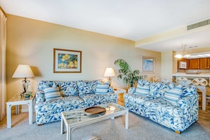 A living room with two sofas, a coffee table, lamps, and artwork on the walls. - Beachfront condo with large furnished balcony, pool & beautiful views (Hilton Head)
