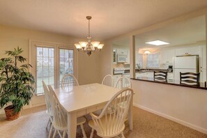 A dining area with a table, chairs, a chandelier, and a potted plant. - Incredible villa with pool and tennis access, central AC, and on-site golf (Hilton Head)