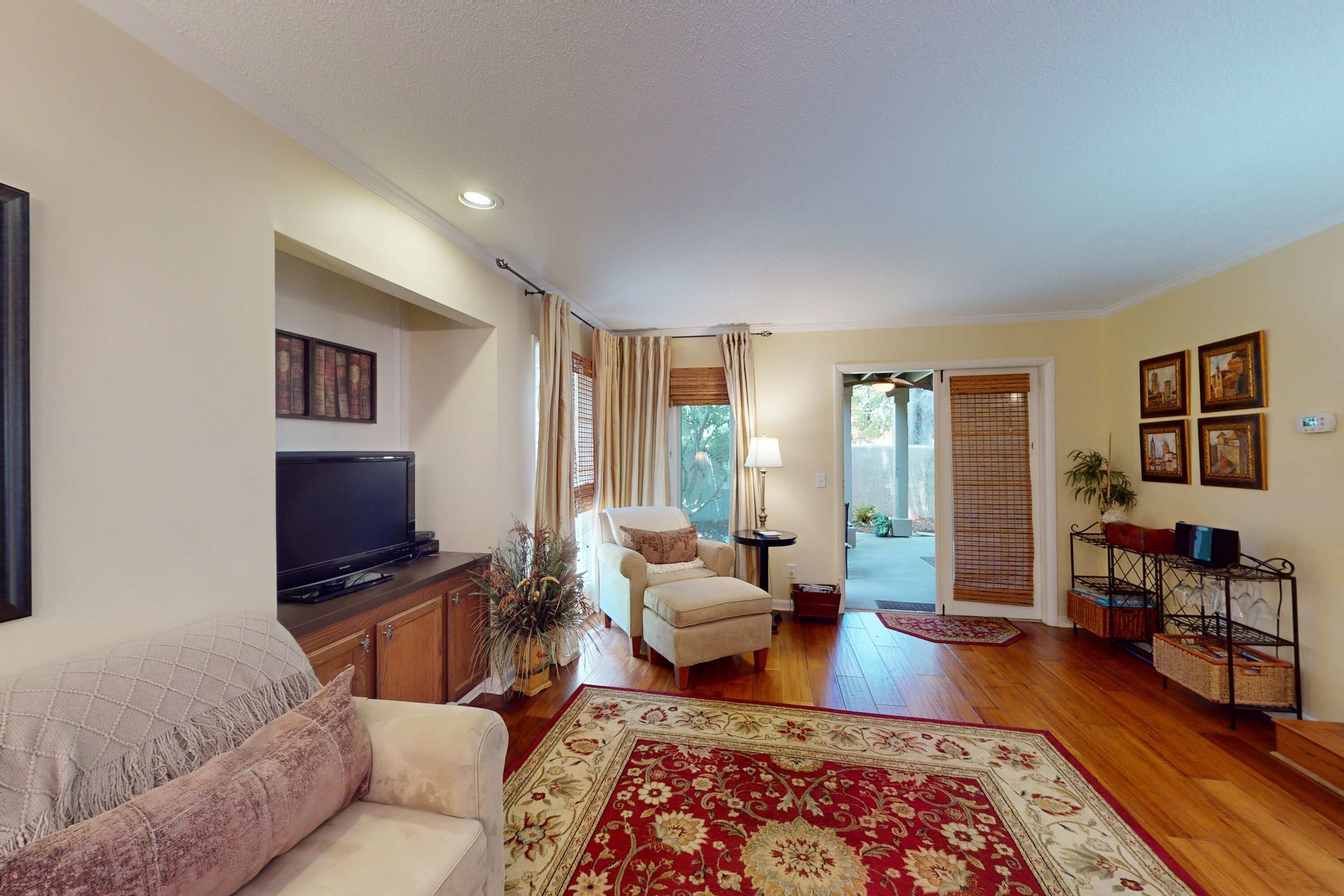 A living room with a sofa, a television, a chair, a rug, and a small table.