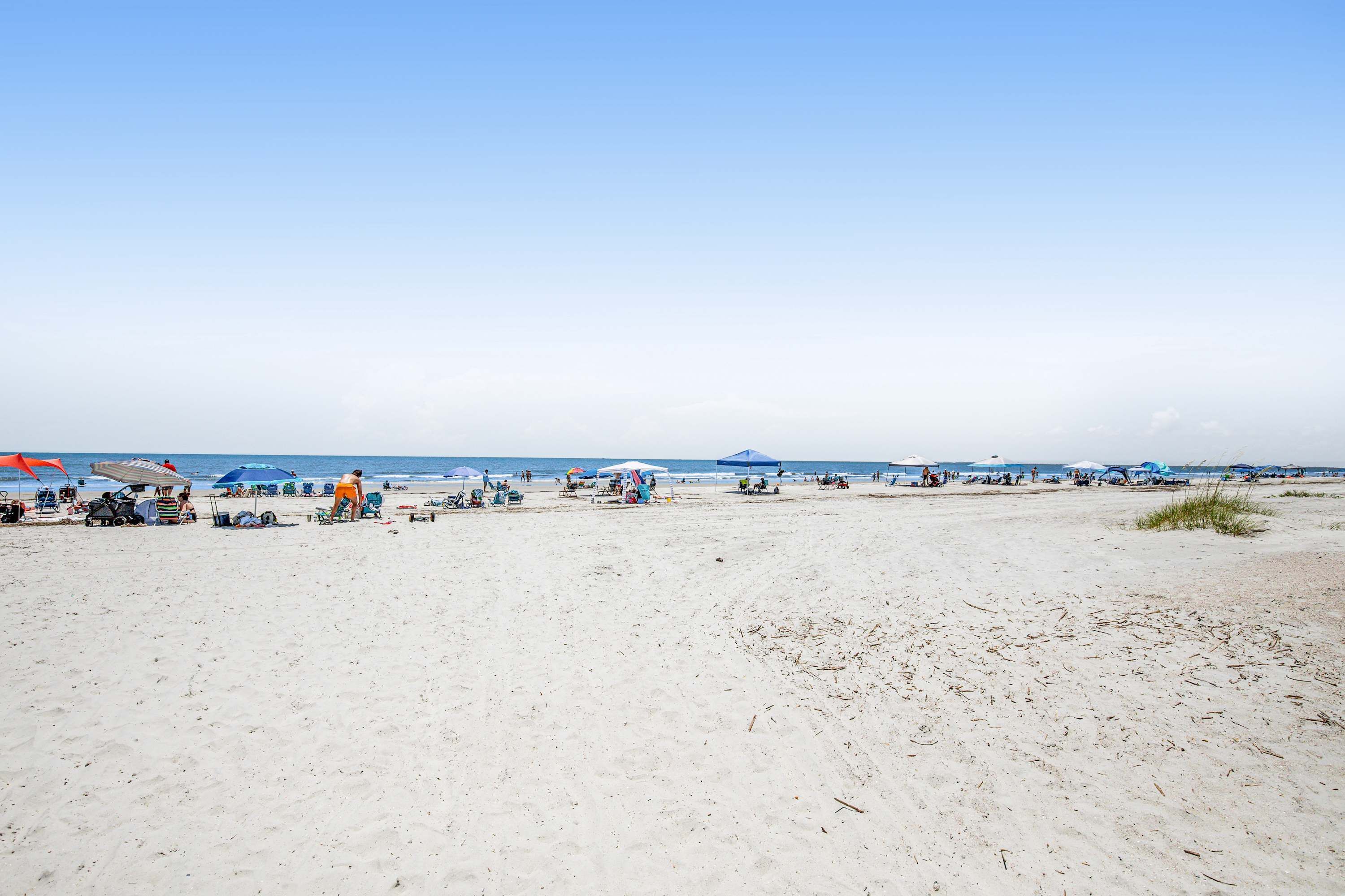 A beach with umbrellas, beach chairs, and people.