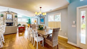 Une salle à manger spacieuse avec une table en bois, des chaises blanches et un lustre.