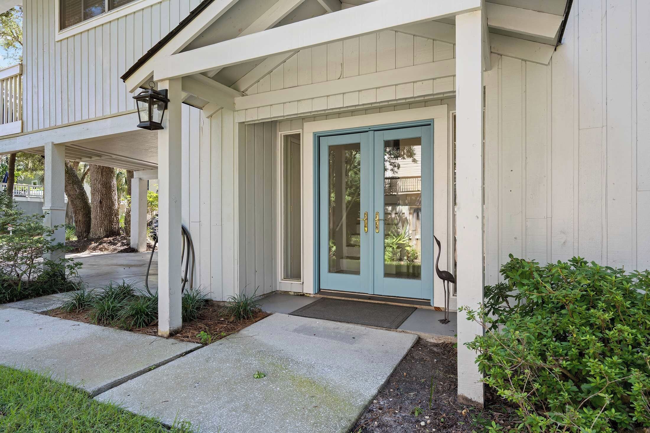 A house with a covered porch, a blue door, and a bird statue.