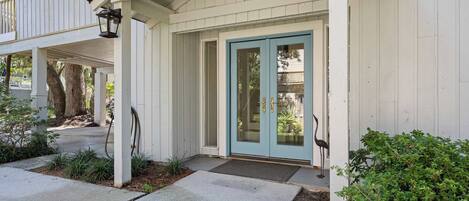 A house with a covered porch, a blue door, and a bird statue.