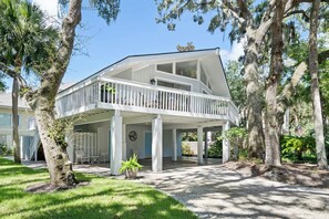 A two-story house with a balcony, surrounded by trees. - North Forest Beach home with large deck, three houses from the beach (Hilton Head)