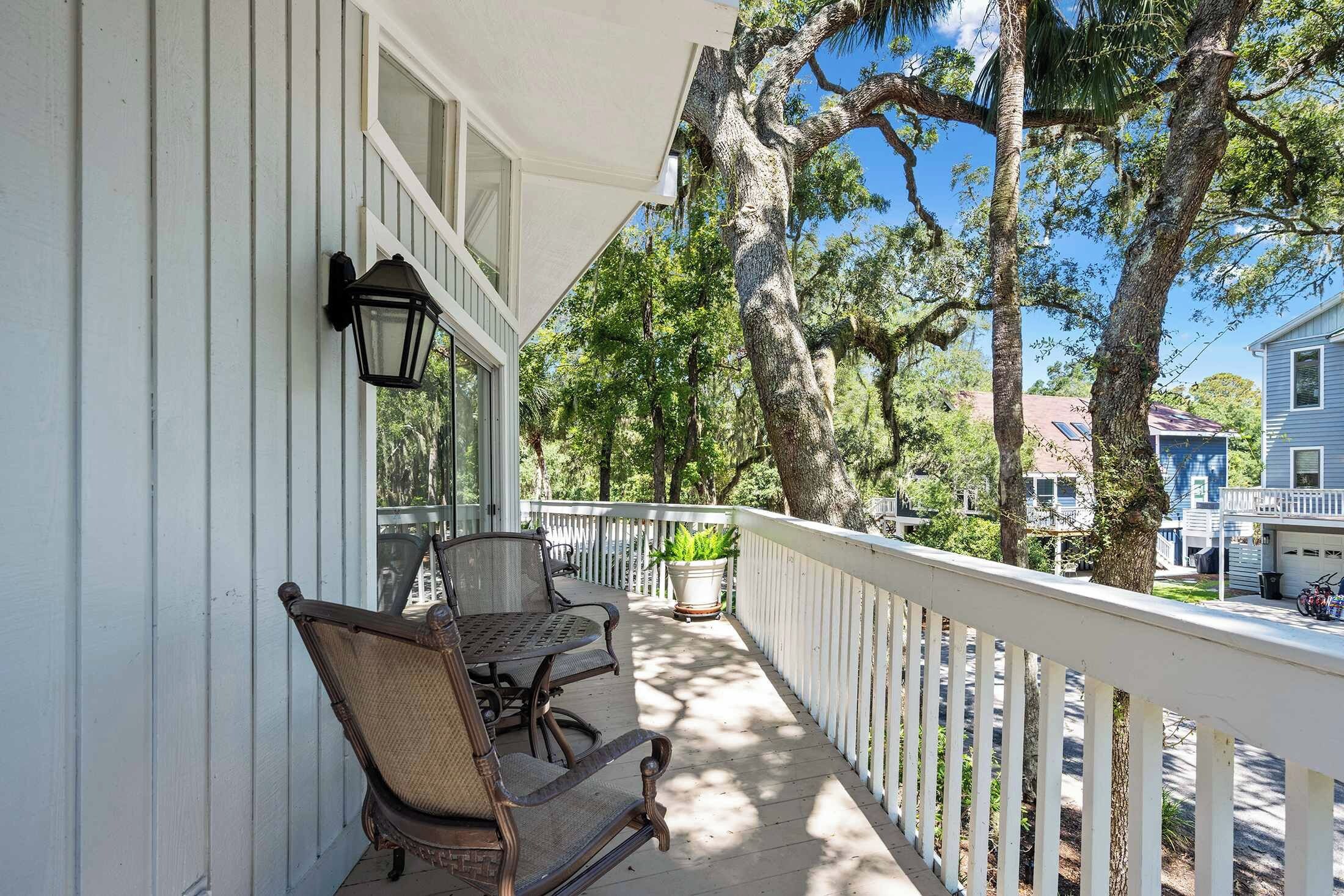 A porch with two wicker chairs, a table, and a potted plant.