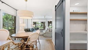 A modern kitchen with a dining area, large windows, and a view of the outdoors. - Scenic Golf Front Condo with Large Deck, Resort Pool & Easy Beach Access (Hilton Head)