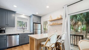 A modern kitchen with grey cabinets, stainless steel appliances, and a wooden island with bar stools. - Scenic Golf Front Condo with Large Deck, Resort Pool & Easy Beach Access (Hilton Head)