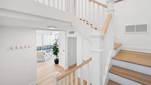 A staircase with white railings and wooden steps leading to an upper level. - Scenic Golf Front Condo with Large Deck, Resort Pool & Easy Beach Access (Hilton Head)
