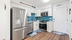 Een moderne keuken met roestvrijstalen apparatuur, witte kasten en blauwe backsplash tegels.