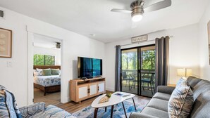Een moderne woonkamer met een bank, een salontafel, een televisie en een eethoek met een tafel en stoelen.