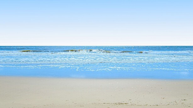 Een strand met helderblauw water en een zandstrand.