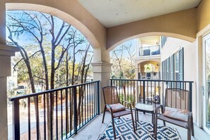 A balcony with two chairs, a table, and a patterned rug. - Lovely villa with balcony, rooftop pool, hot tub, & parking - 1 block to beach (Hilton Head)