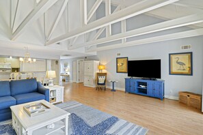 A spacious living room with a sofa, coffee table, and entertainment unit. - Spacious Palmetto Dunes Condo, Sunny Deck,  View of Lagoon, Complex Pool (Hilton Head)