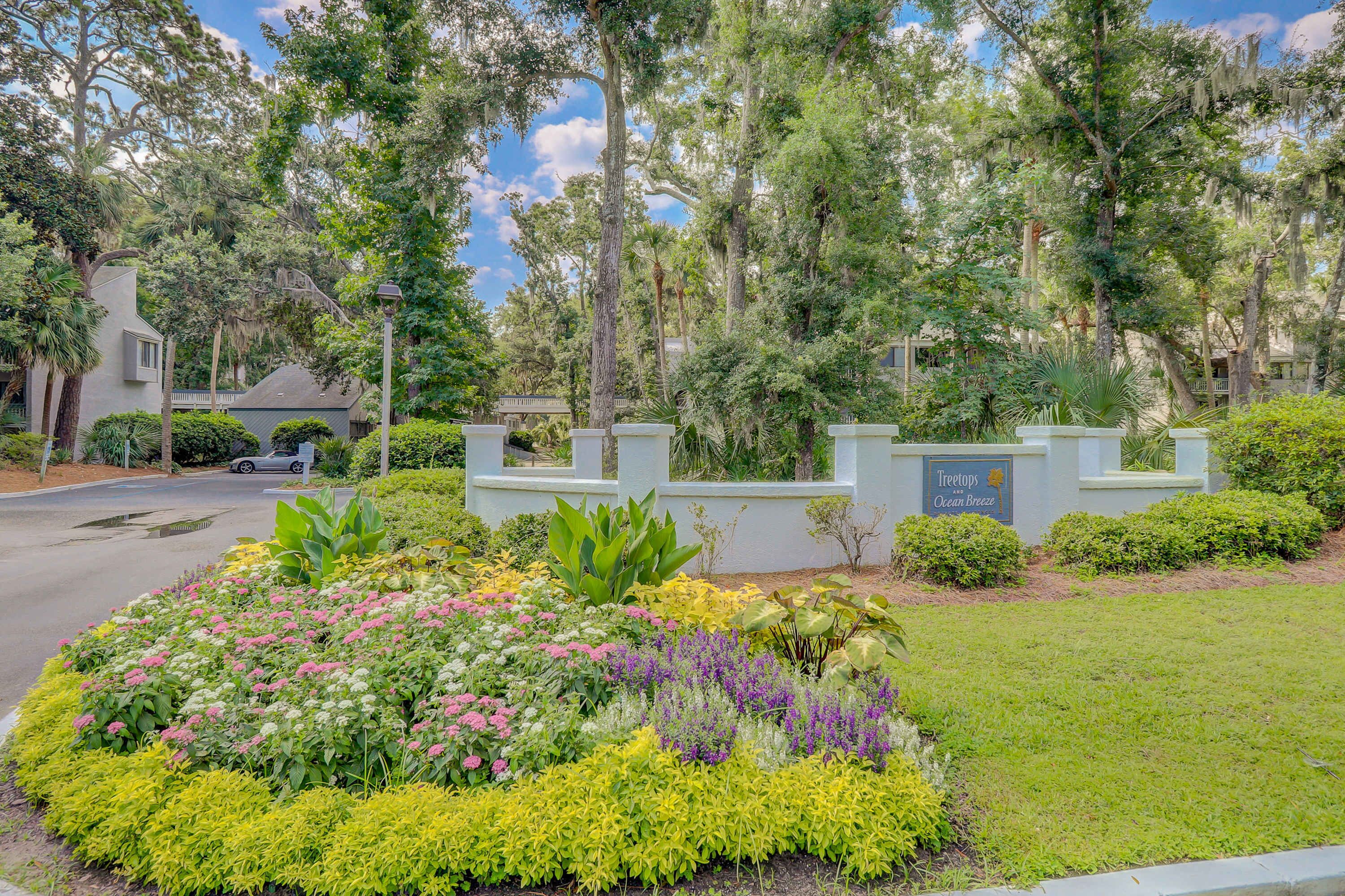 Zona ajardinada con diversas plantas y un letrero que dice 'Treetops Ocean Breeze'.