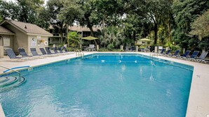 A swimming pool with lounge chairs and a lifeguard stand. - Pool view condo with screened in patio, complex pool hot tub, near golf (Hilton Head)