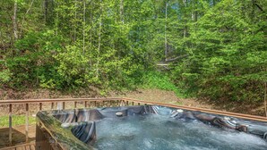 Un bain à remous entouré d’une terrasse en bois et d’une forêt.