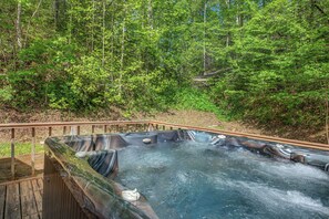 A hot tub surrounded by a wooden deck and forest. - Escape to the serene beauty of the Smoky Mountains, Shiner's Hollow. (Gatlinburg)