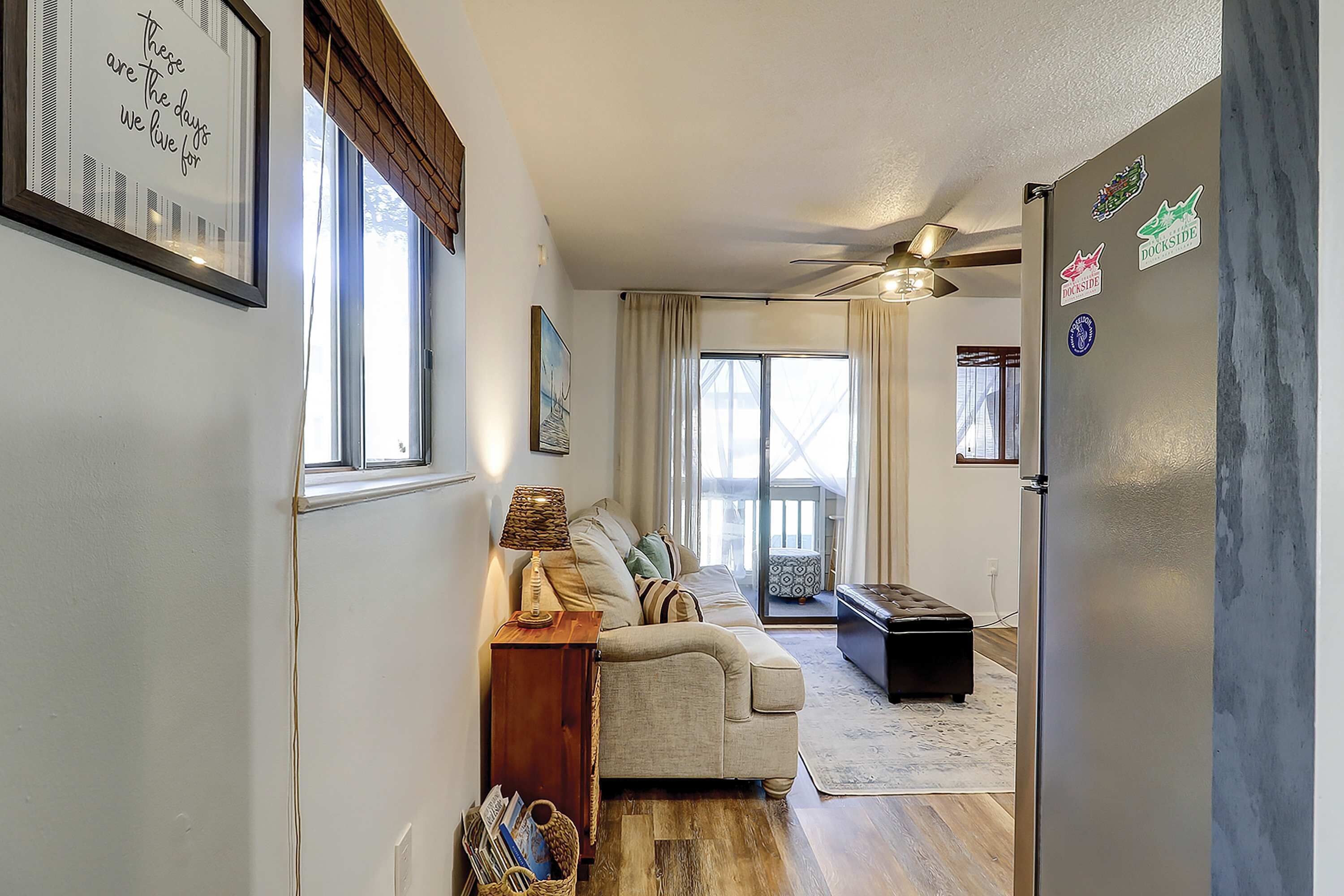 A living room with a sofa, a coffee table, a lamp, and a refrigerator.