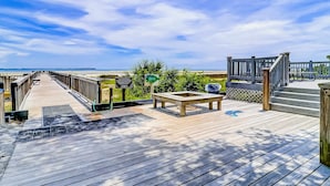 Eine Holzterrasse mit einer Bank, einem Mülleimer und einem Wegweiser.