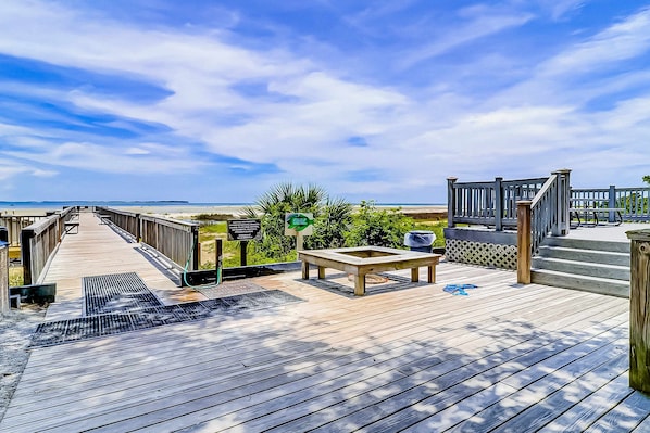 A wooden deck with a bench, a trash bin, and a sign indicating a direction.