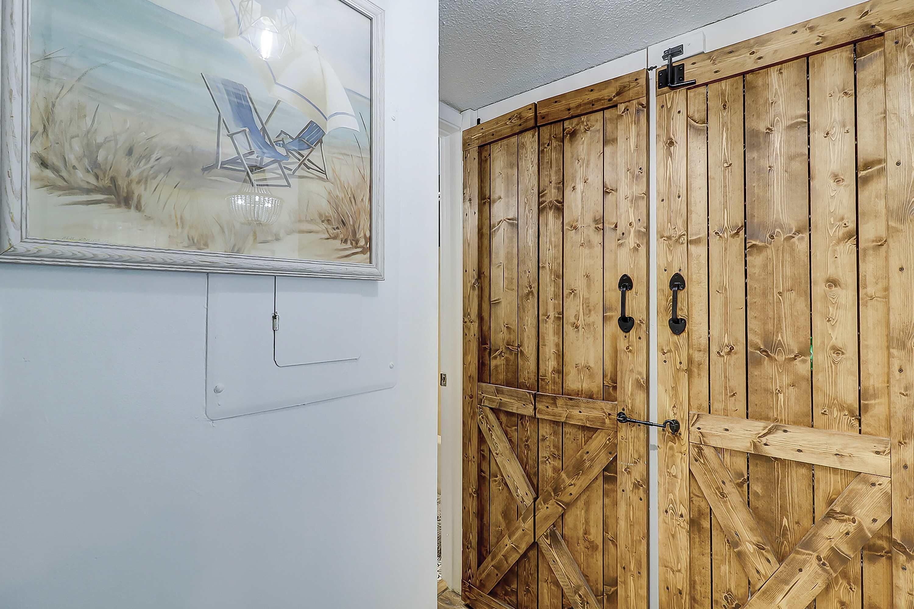 A room with a wooden door, a framed picture on the wall, and a light switch.