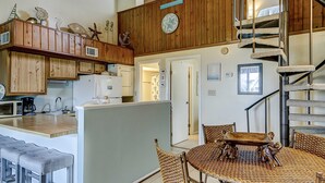 A kitchen with wooden cabinets, a microwave, and a dining area with wicker chairs and a wooden table. - Top-floor villa with fairway views - central AC, private W/D, WiFi - Dogs OK (Edisto Beach)