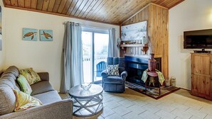 A living room with a sofa, a chair, a round table, a fireplace, and a television. - Top-floor villa with fairway views - central AC, private W/D, WiFi - Dogs OK (Edisto Beach)