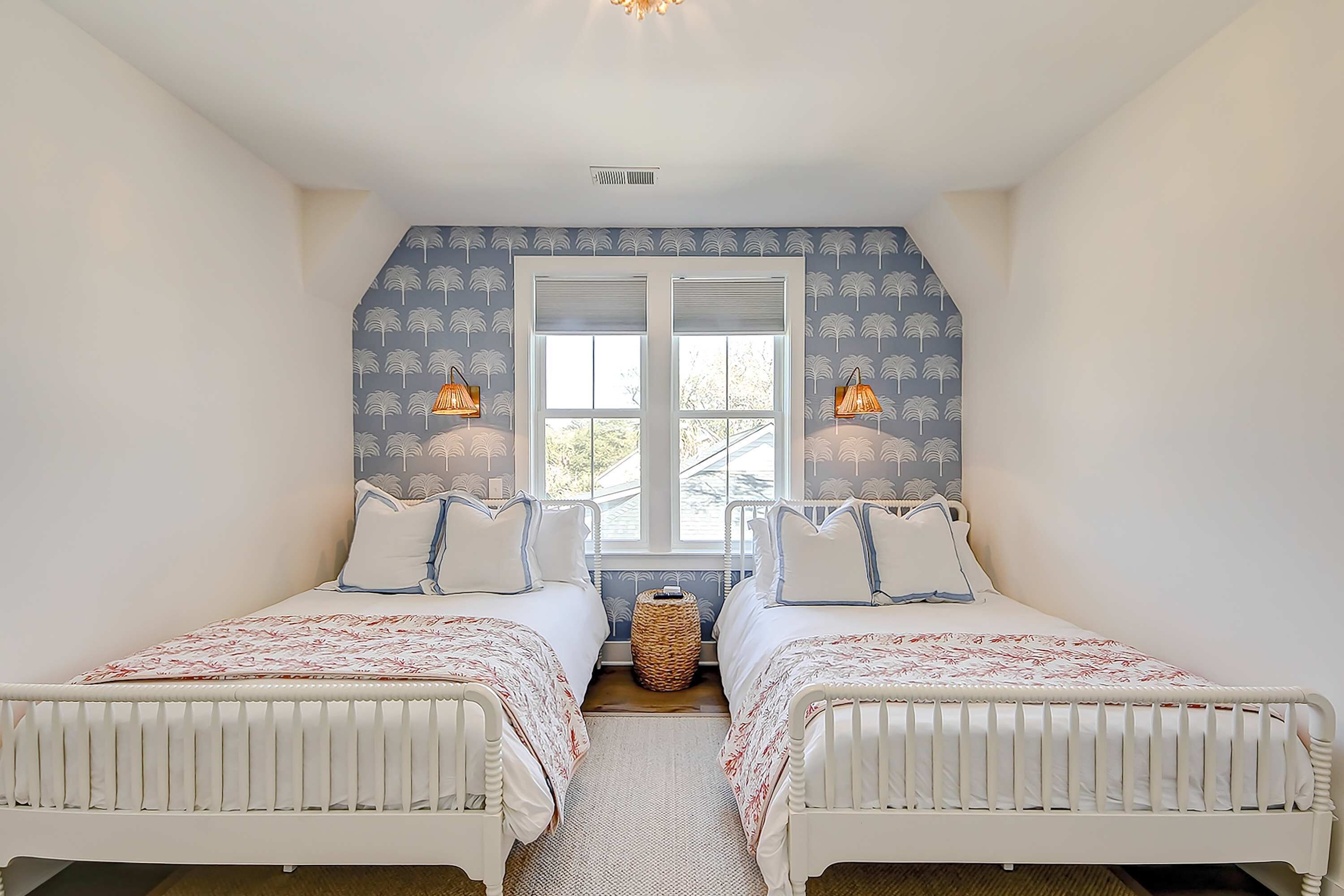 Un dormitorio con dos camas, una ventana y dos lámparas de pared.