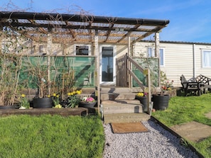 A residential property with a covered porch, a wooden fence, and potted plants. - Cornholme Lodge (Accrington)