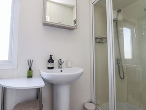 A bathroom with a sink, mirror, and shower. - Cornholme Lodge (Accrington)
