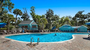 A swimming pool with lounge chairs and a building with a sign. - Spacious home near beach with access to resort amenities & free state park entry (Edisto Beach)