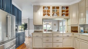A kitchen with dark cabinets, a white island, and a glass-fronted upper cabinet. - Spacious home near beach with access to resort amenities & free state park entry (Edisto Beach)
