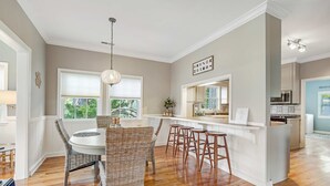 A modern kitchen with a dining area, wooden flooring, and a pendant light. - Spacious home near beach with access to resort amenities & free state park entry (Edisto Beach)