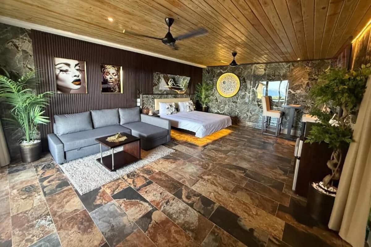 A modern room with a sofa, a bed, a coffee table, and a dining area.