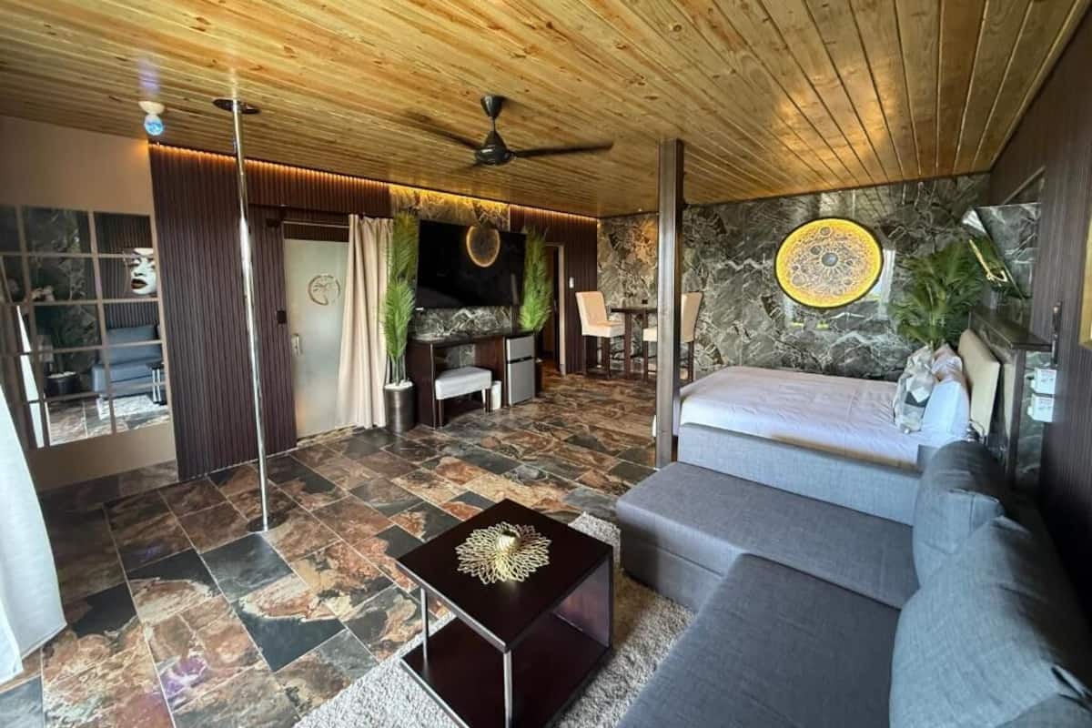 A modern living room with a stone floor, a wooden ceiling, a sofa, a coffee table, and a TV.