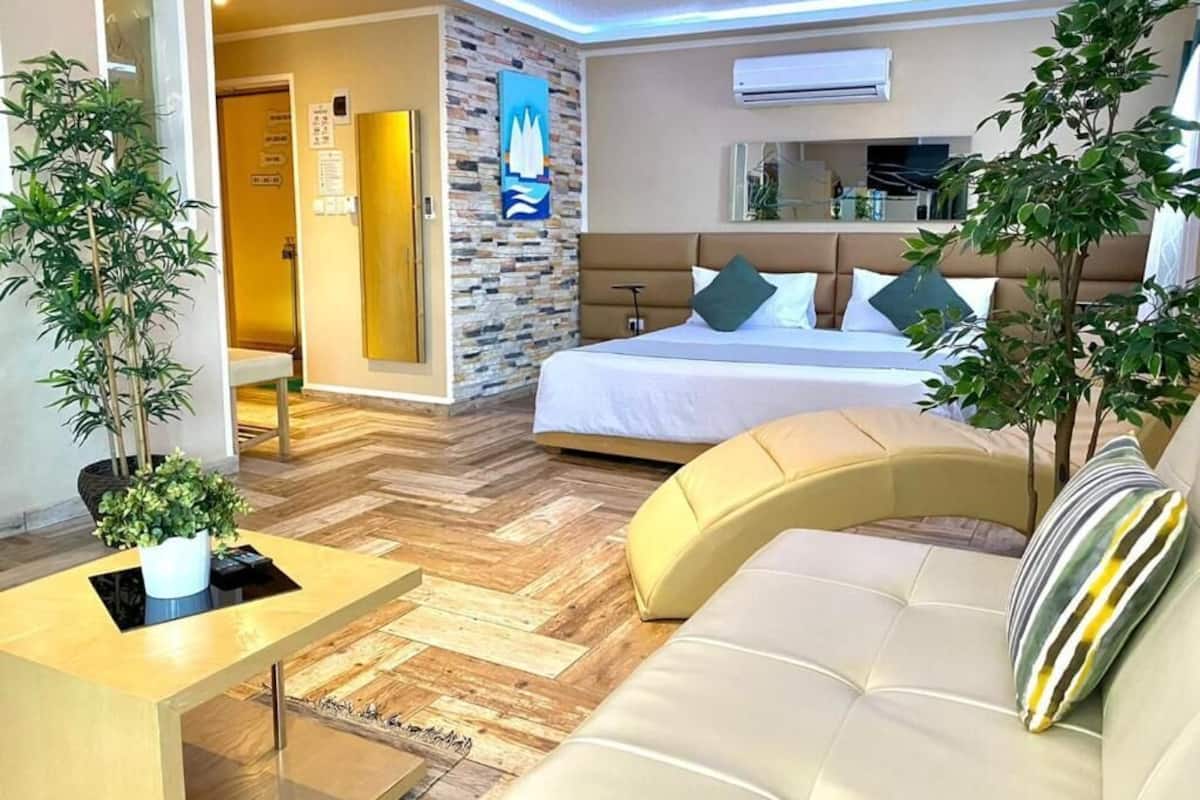 A modern hotel room with a bed, sofa, and a small table.