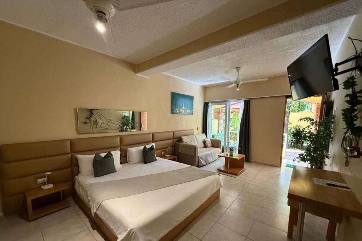 A hotel room with a bed, a sofa, a TV, and a desk.