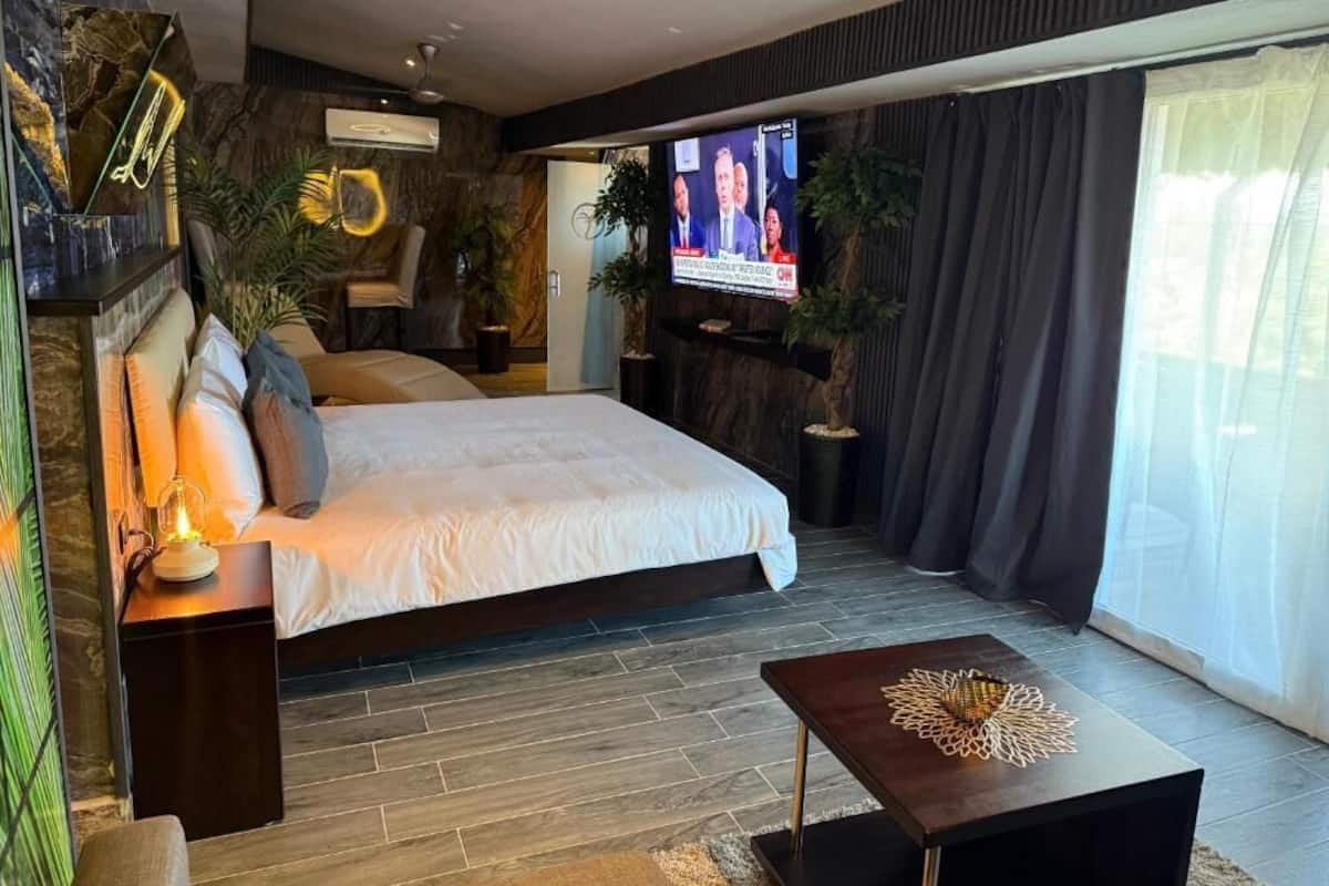 A modern bedroom with a large bed, a TV, and a small table.