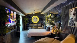 Une chambre d’hôtel moderne équipée d’un lit, d’un canapé, d’une télévision et d’un luminaire circulaire original.