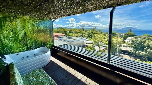 Une salle de bain moderne avec une grande baignoire, un plancher en bois et une vue sur le paysage urbain, visible à travers de grandes fenêtres.