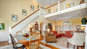 A spacious living area with a dining table, chairs, a sofa, and a staircase leading to an upper level. - Charming Home w/ Lagoon View, WiFi, Laundry, Central AC - Walk to the Beach (Edisto Beach)