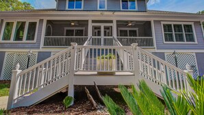 Ein zweistöckiges Haus mit Veranda, Treppe und einem kleinen Garten.