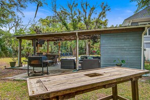 An outdoor patio with a grill, seating, and a covered area. - Edisto Hidden Oasis (Edisto Island)