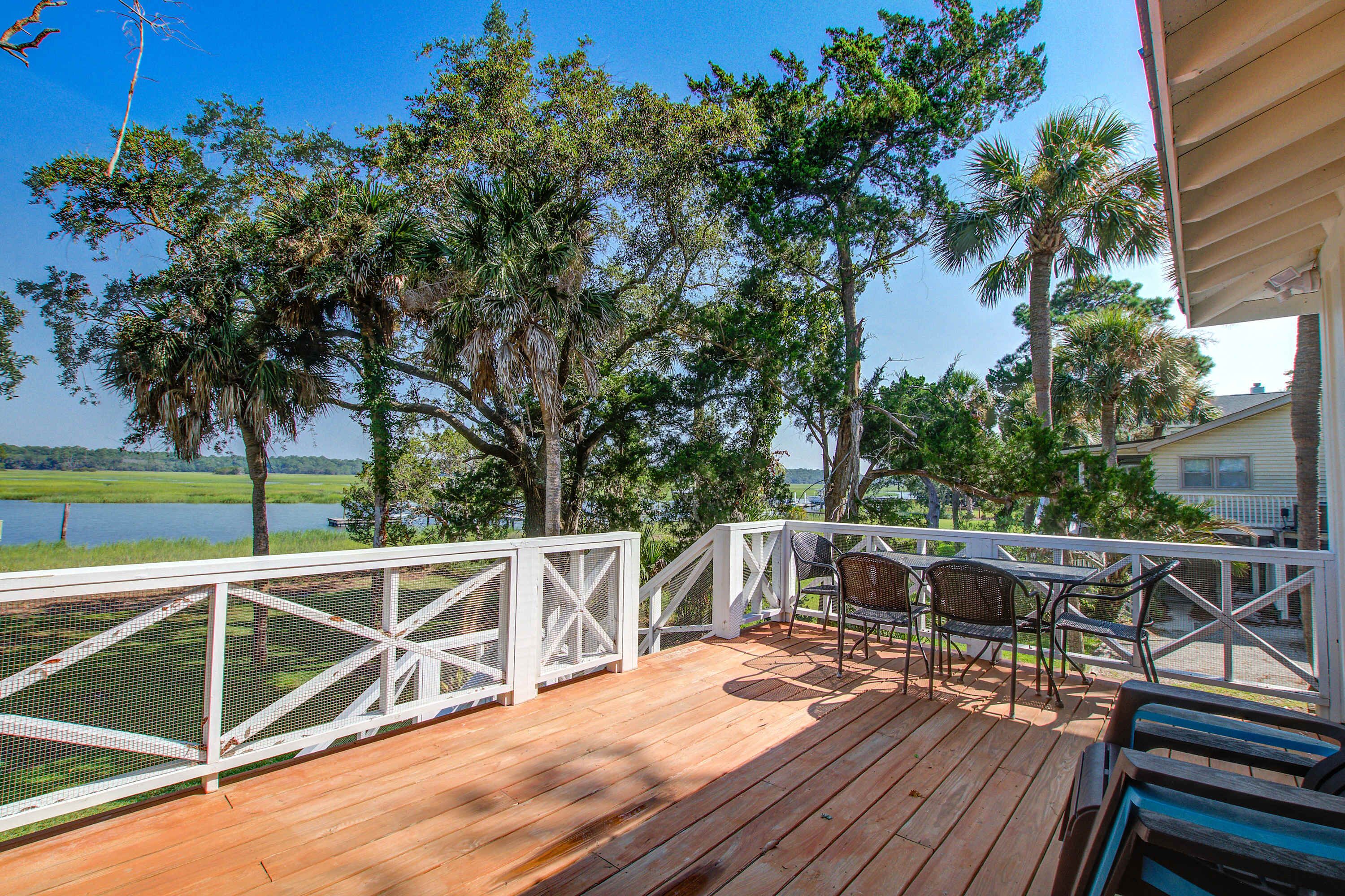 A wooden deck with a white railing, outdoor furniture, and a view of a lake.