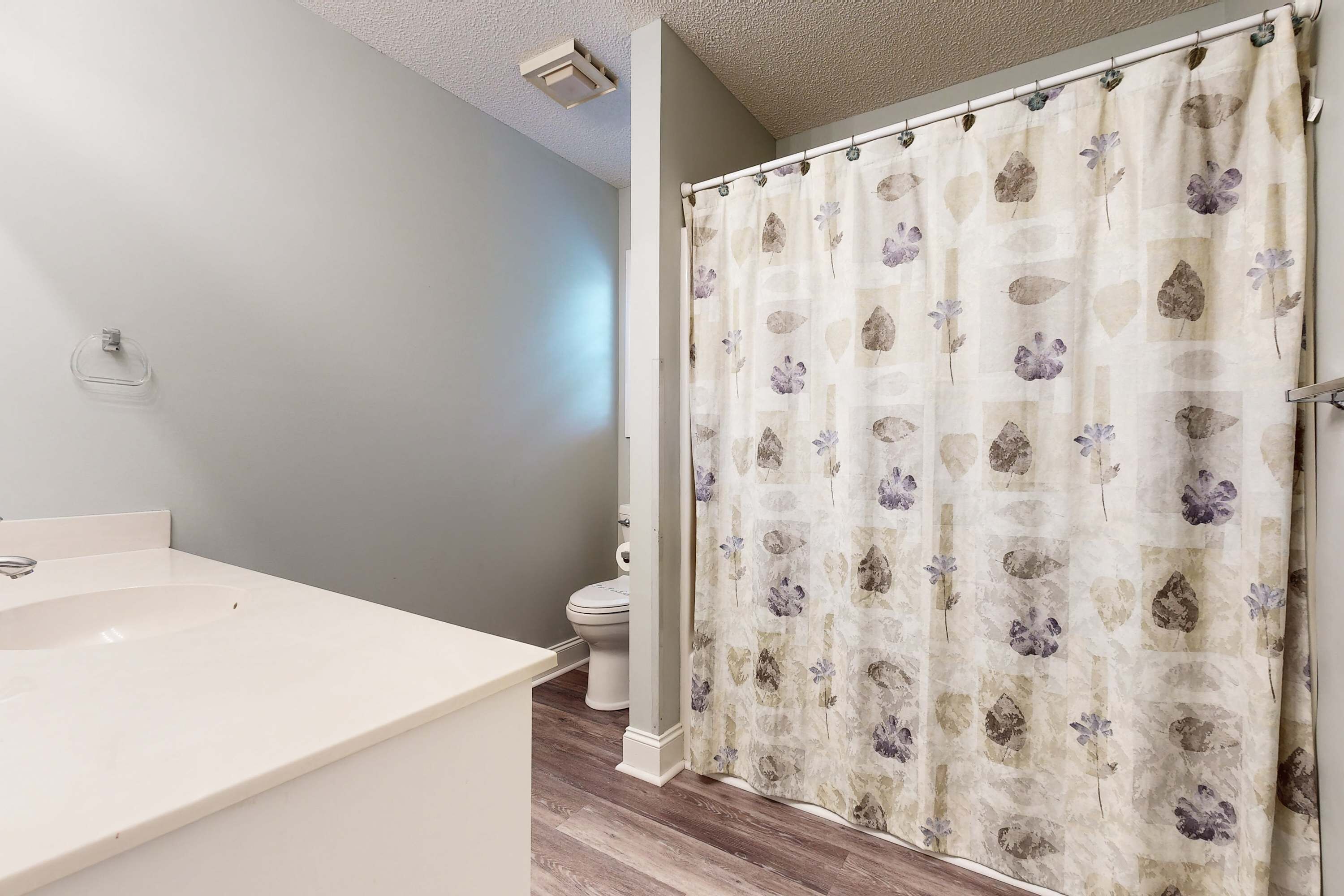 A bathroom with a white sink, a toilet, and a shower curtain with a floral pattern.