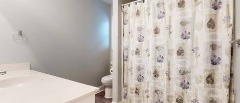 A bathroom with a white sink, a toilet, and a shower curtain with a floral pattern.