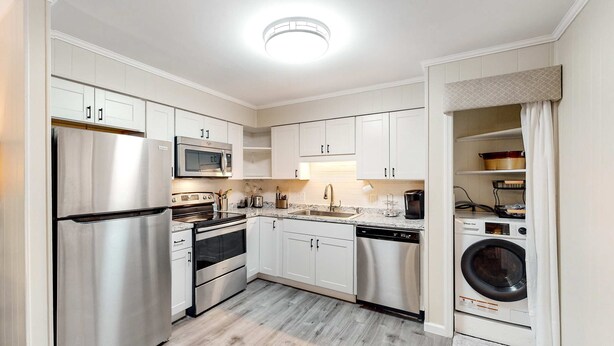 A modern kitchen with stainless steel appliances, white cabinetry, and a built-in washing machine. - The Hedges D1 Condo in Hilton Head with pool & tennis, walk to the beach (Hilton Head)