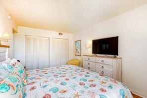 Quarto com cama, televisão, cómoda e armário.