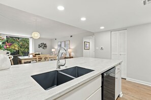 Une cuisine moderne dotée d’un îlot central, d’un lave-vaisselle encastré et d’un coin repas avec une table et des chaises.
